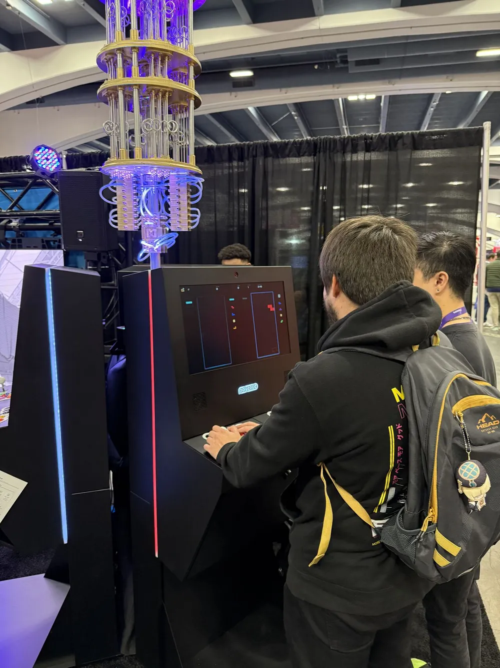 Two attendees playing a Quantum Forge title on the Quantum Arcade cabinet at GDC 2026